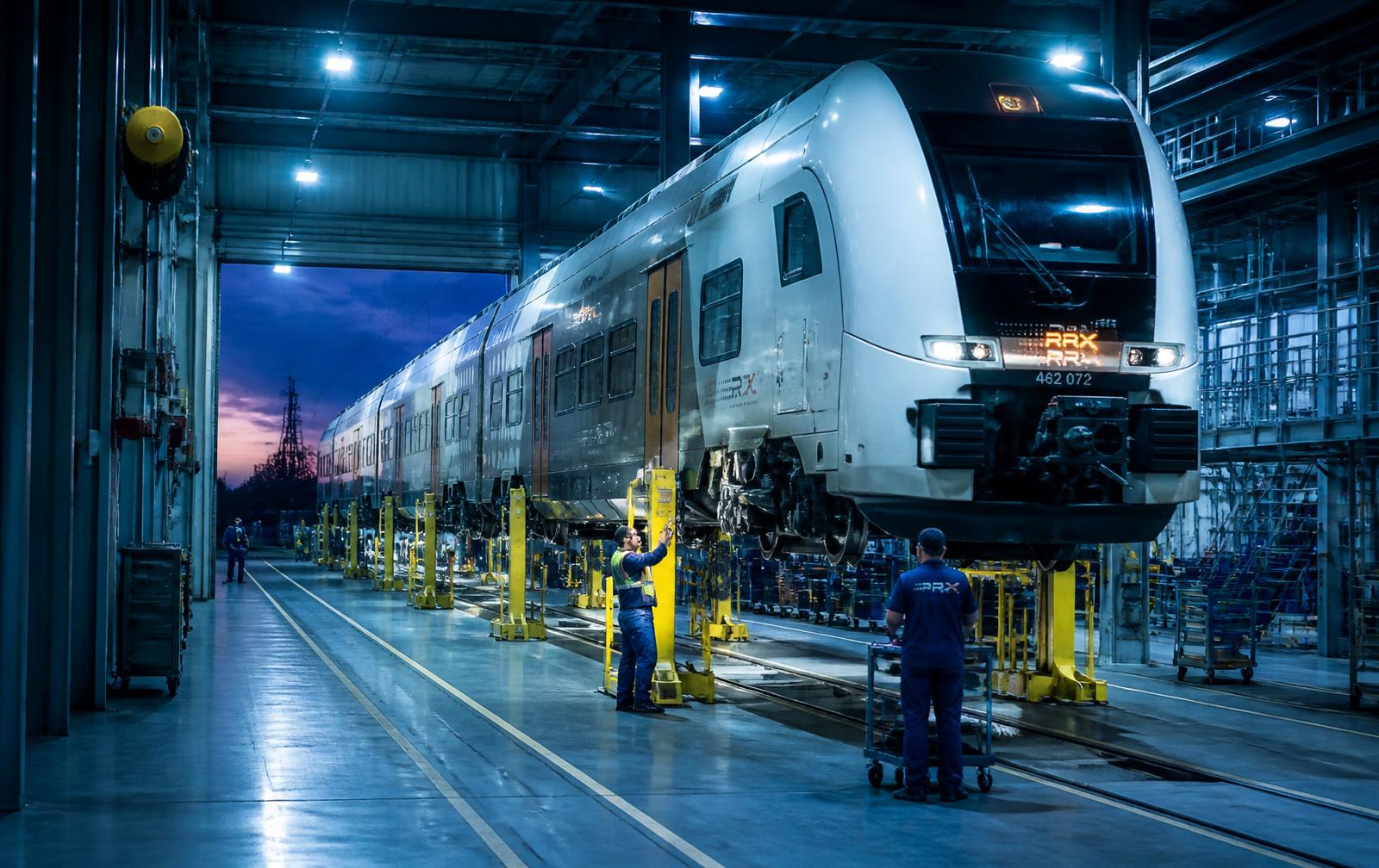 Modern rail depot workshop with a regional train raised on maintenance jacks and technicians at work